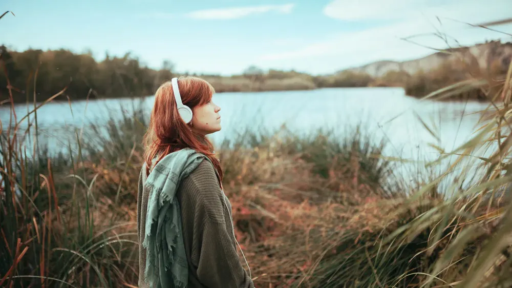 woman with headphones at lake.